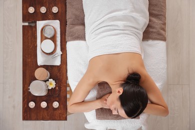 Photo of Young woman resting after professional massage in spa salon, top view