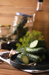 Photo of Fresh cucumbers and other ingredients prepared for canning on wooden table, closeup