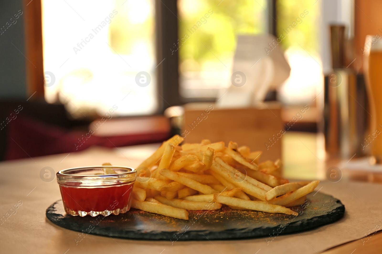 Photo of Delicious hot french fries with red sauce served on table