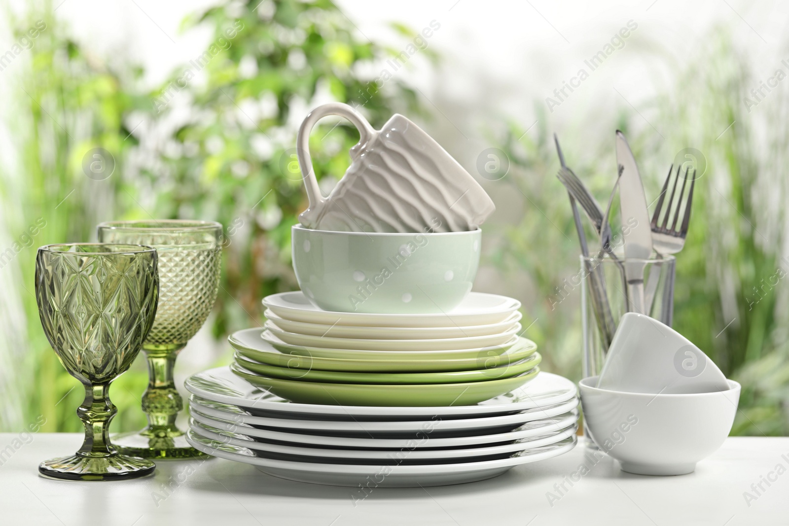 Photo of Beautiful ceramic dishware, glasses, cutlery and cup on white marble table outdoors