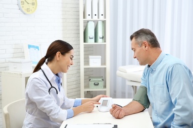 Photo of Doctor checking mature man's pulse with medical device in hospital