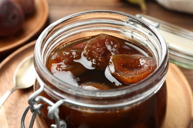 Jar of tasty sweet fig jam on table, closeup