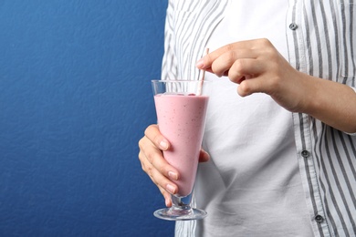 Image of Woman with glass of tasty smoothie on blue background, closeup