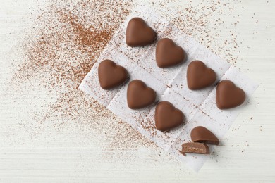 Photo of Beautiful heart shaped chocolate candies on white wooden table, flat lay