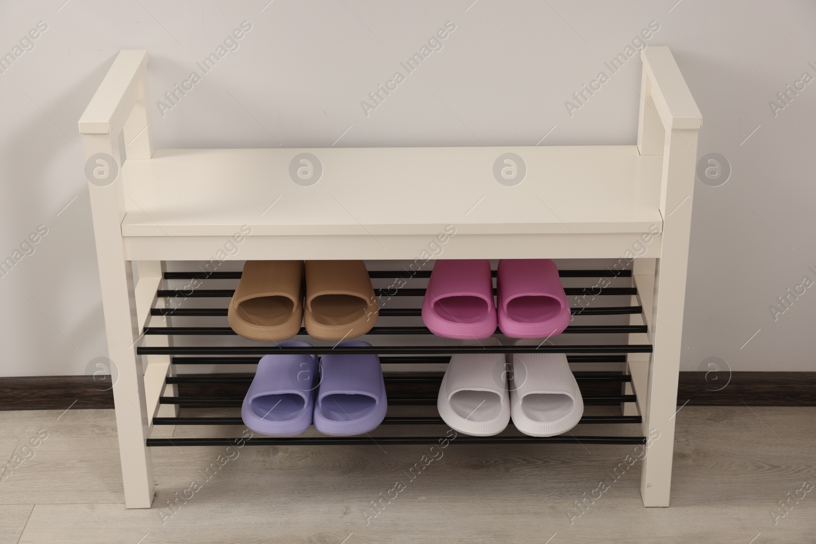 Photo of Storage bench with pairs of rubber slippers indoors