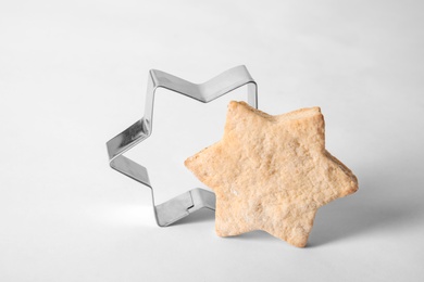 Photo of Tasty homemade Christmas cookie and cutter on white background