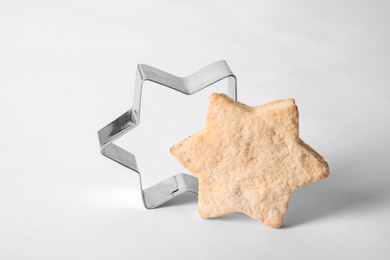 Tasty homemade Christmas cookie and cutter on white background