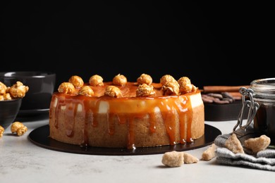 Photo of Sliced delicious cheesecake with caramel and popcorn on light grey table