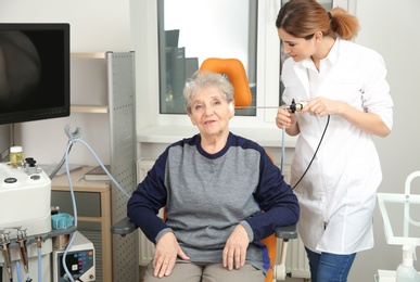 Professional otolaryngologist examining senior woman with endoscope in clinic. Hearing disorder