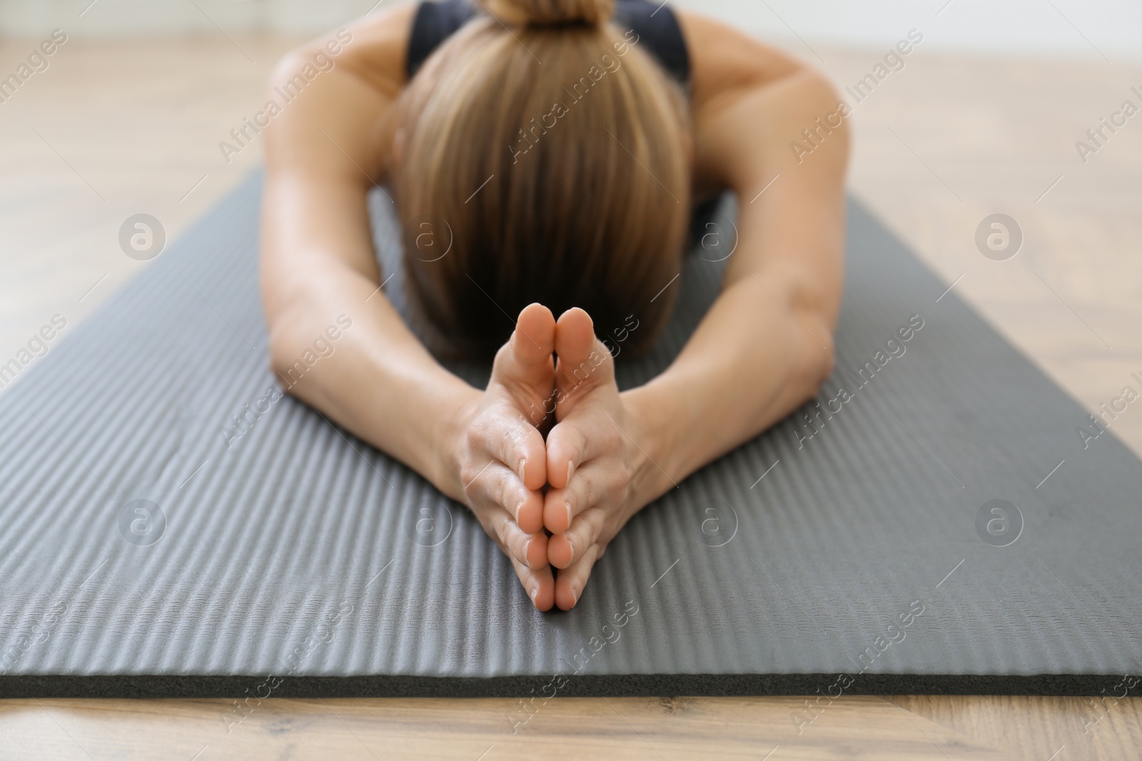 Photo of Young woman practicing extended child asana in yoga studio, focus on hands. Utthita Balasana pose