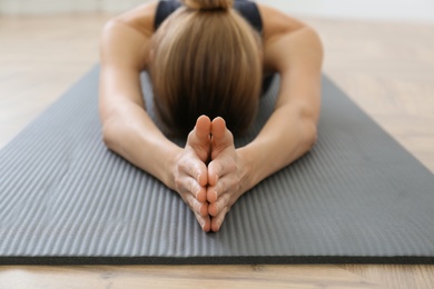 Young woman practicing extended child asana in yoga studio, focus on hands. Utthita Balasana pose