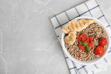 Photo of Tasty buckwheat porridge with meat on grey marble table, top view. Space for text