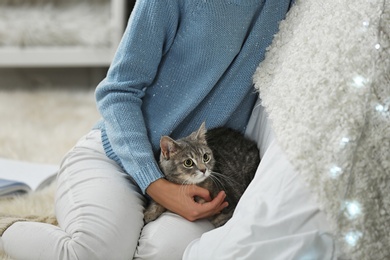 Photo of Young woman with cute cat at home, closeup. Cozy winter