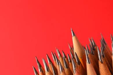 Photo of Sharp graphite pencils on red background, space for text