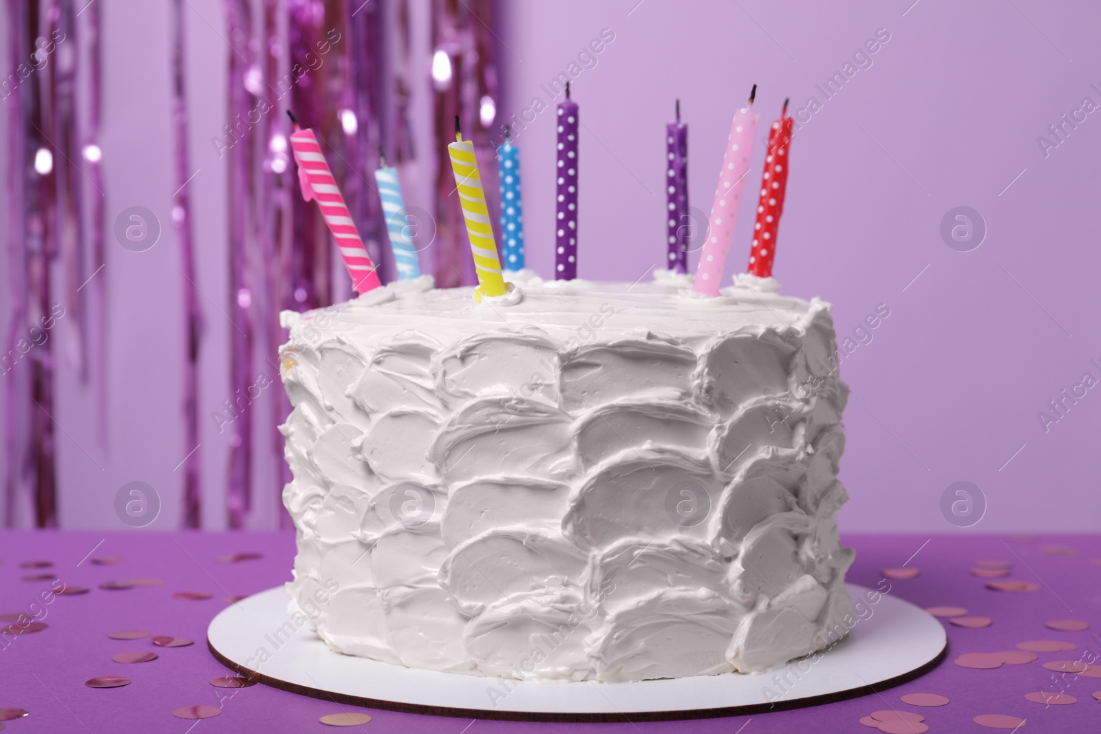 Photo of Delicious cake with cream and burning candles on purple background