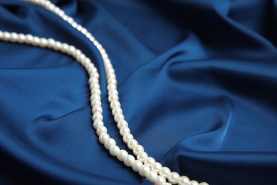 Photo of Beautiful pearls on delicate dark blue silk