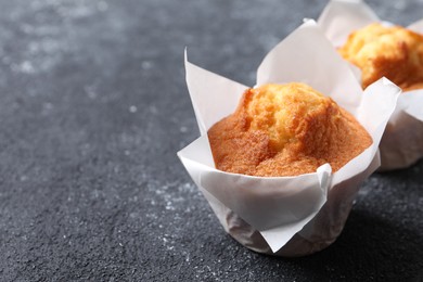 Photo of Delicious sweet muffins on black textured table, closeup. Space for text