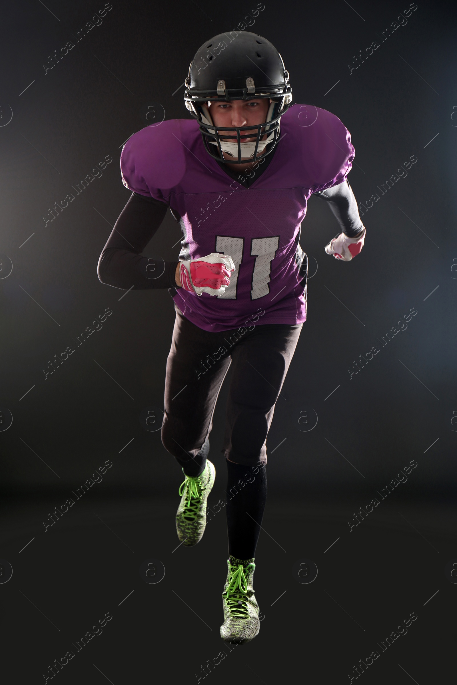 Photo of American football player wearing uniform on dark background