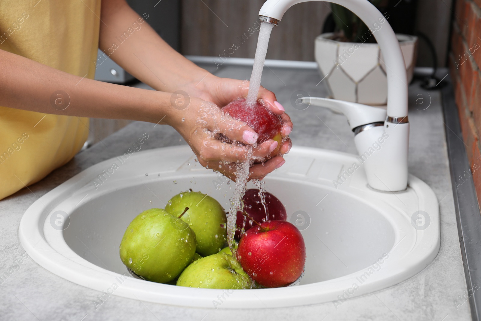 Photo of Woman washing fresh apples in kitchen sink, closeup