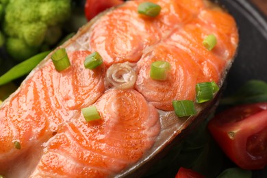 Photo of Healthy meal. Grilled salmon steak, green onion and vegetables on table, closeup
