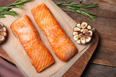 Photo of Delicious roasted fish on wooden table, flat lay