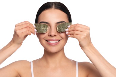 Photo of Beautiful young woman putting green tea bags on eyes against white background