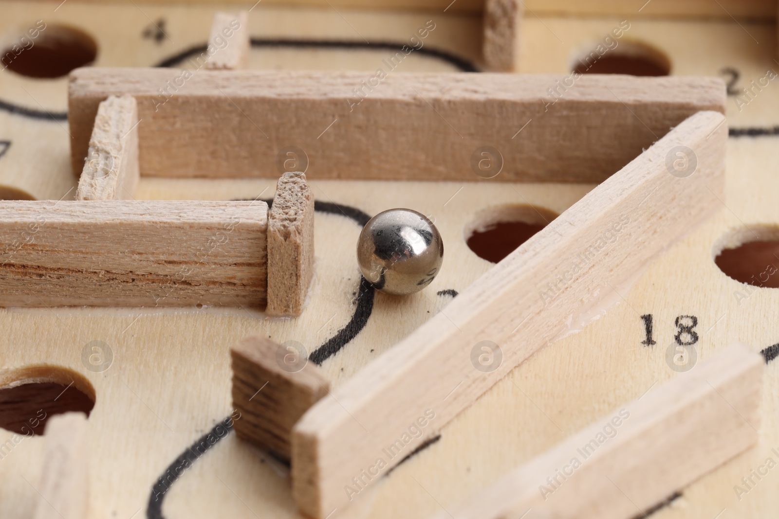 Photo of Wooden toy maze with metal ball, closeup
