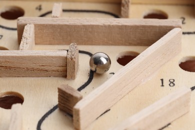 Photo of Wooden toy maze with metal ball, closeup