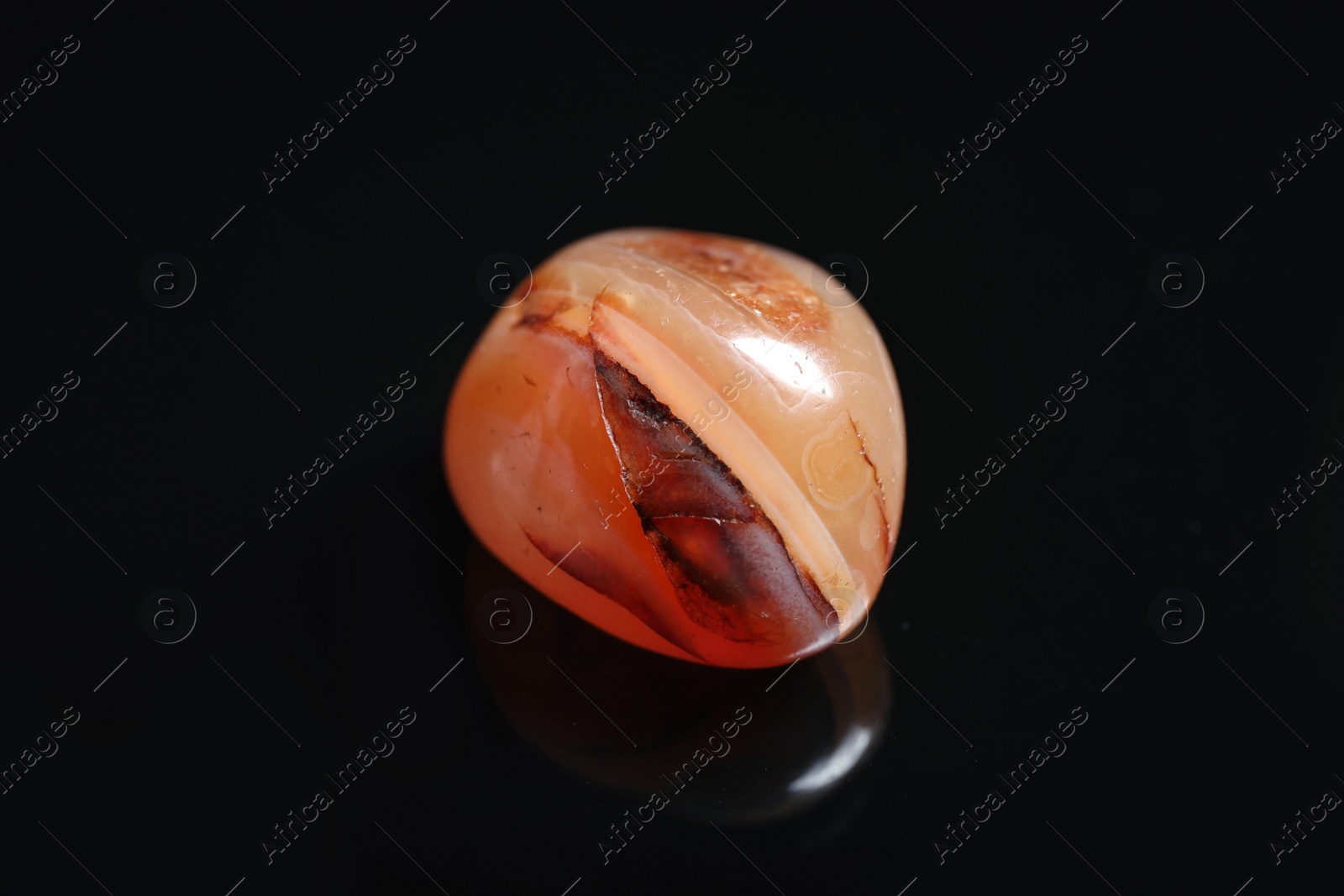 Photo of Beautiful red carnelian agate gemstone on black background