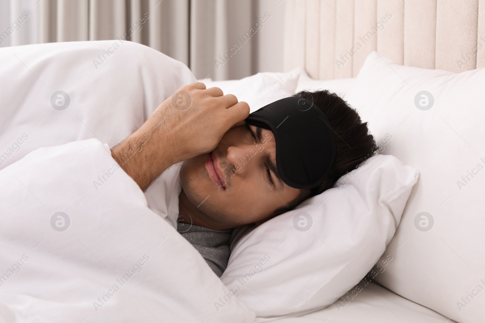 Photo of Man with sleeping mask in bed at home