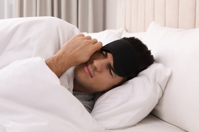 Man with sleeping mask in bed at home