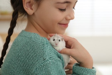 Photo of Little girl with cute hamster at home, closeup