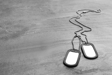 Photo of Metal military ID tags on grey table. Space for text