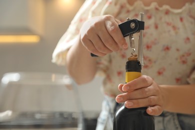 Photo of Woman opening wine bottle with corkscrew on blurred background, closeup. Space for text