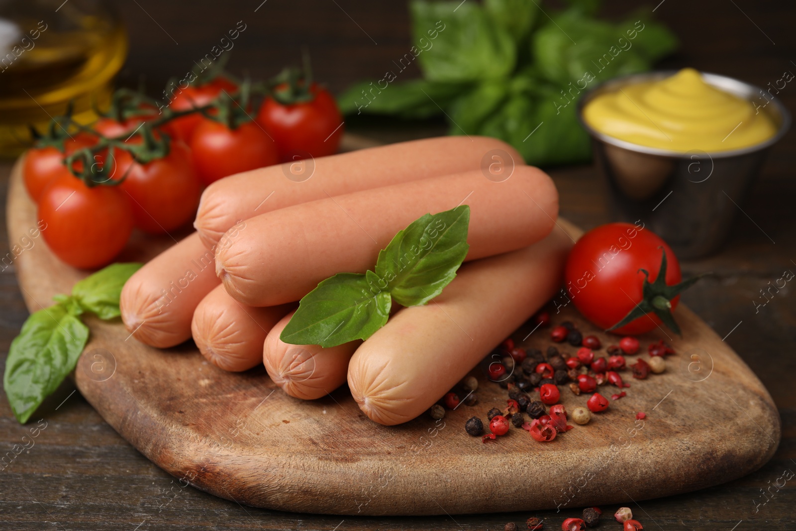 Photo of Delicious boiled sausages, tomatoes, basil and peppercorns on wooden table, closeup