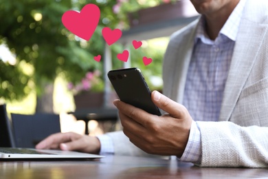 Man visiting dating site via smartphone in outdoor cafe, closeup