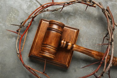 Photo of Crown of thorns and judge gavel on grey table, flat lay