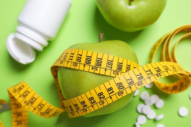 Photo of Flat lay composition with apples and measuring tape on green background. Weight loss