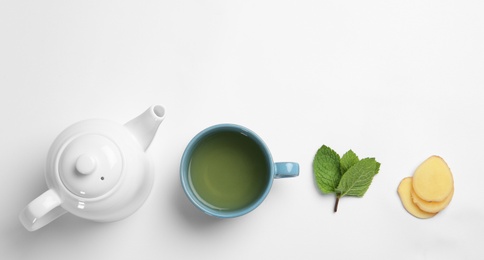 Photo of Cup with hot tea, ginger and teapot on white background, top view. Space for text