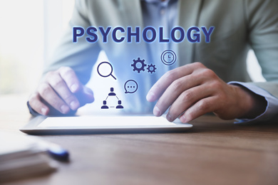 Psychologist working with modern tablet at wooden table in office, closeup 