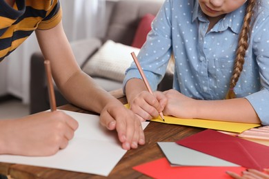 Children making beautiful greeting cards at table indoors, closeup