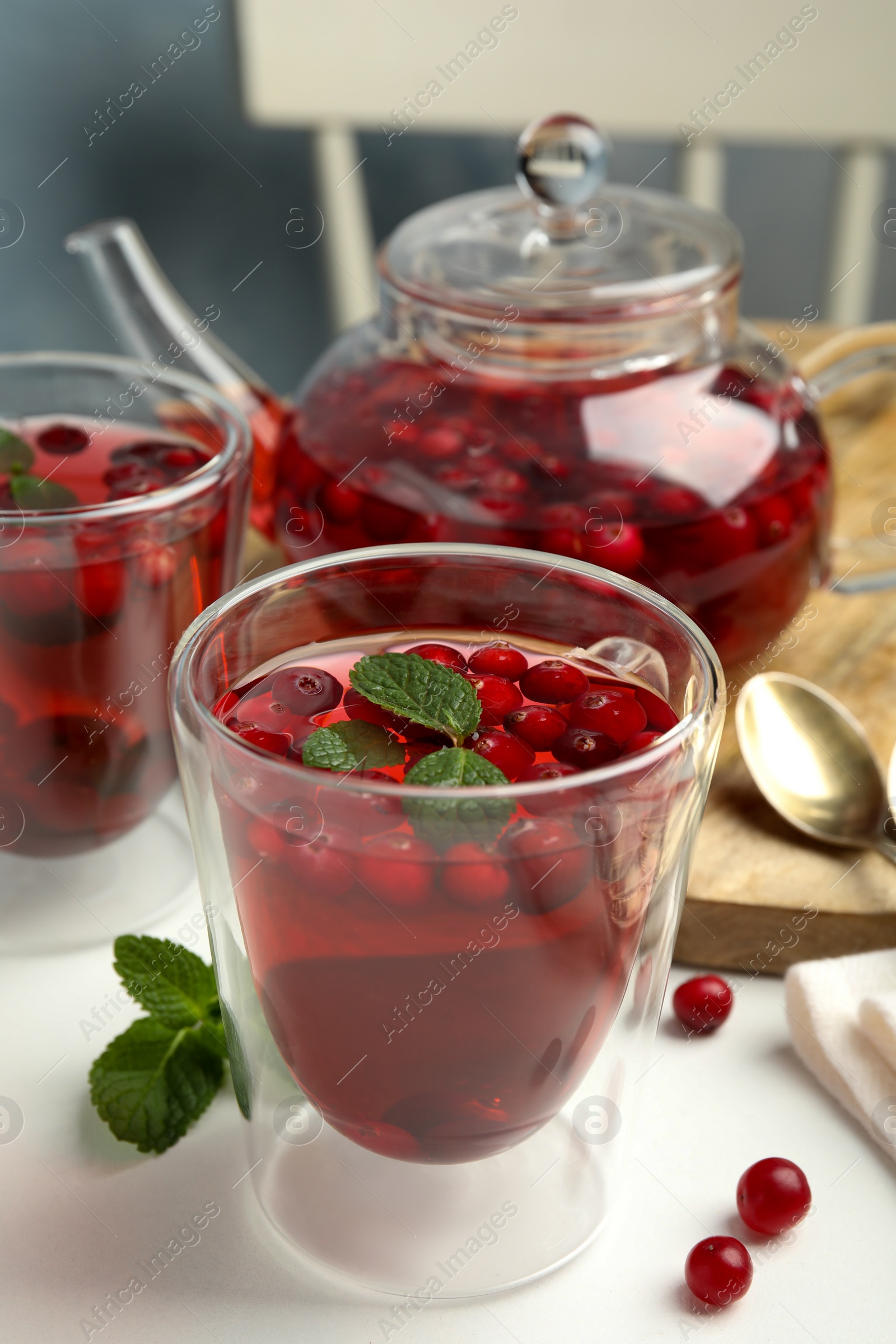 Photo of Tasty hot cranberry tea with mint on light table