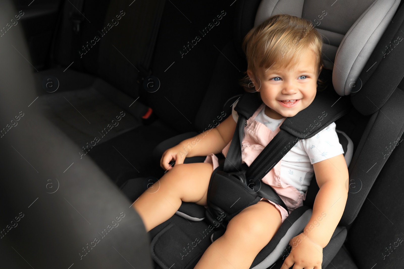 Photo of Cute little girl sitting in child safety seat inside car