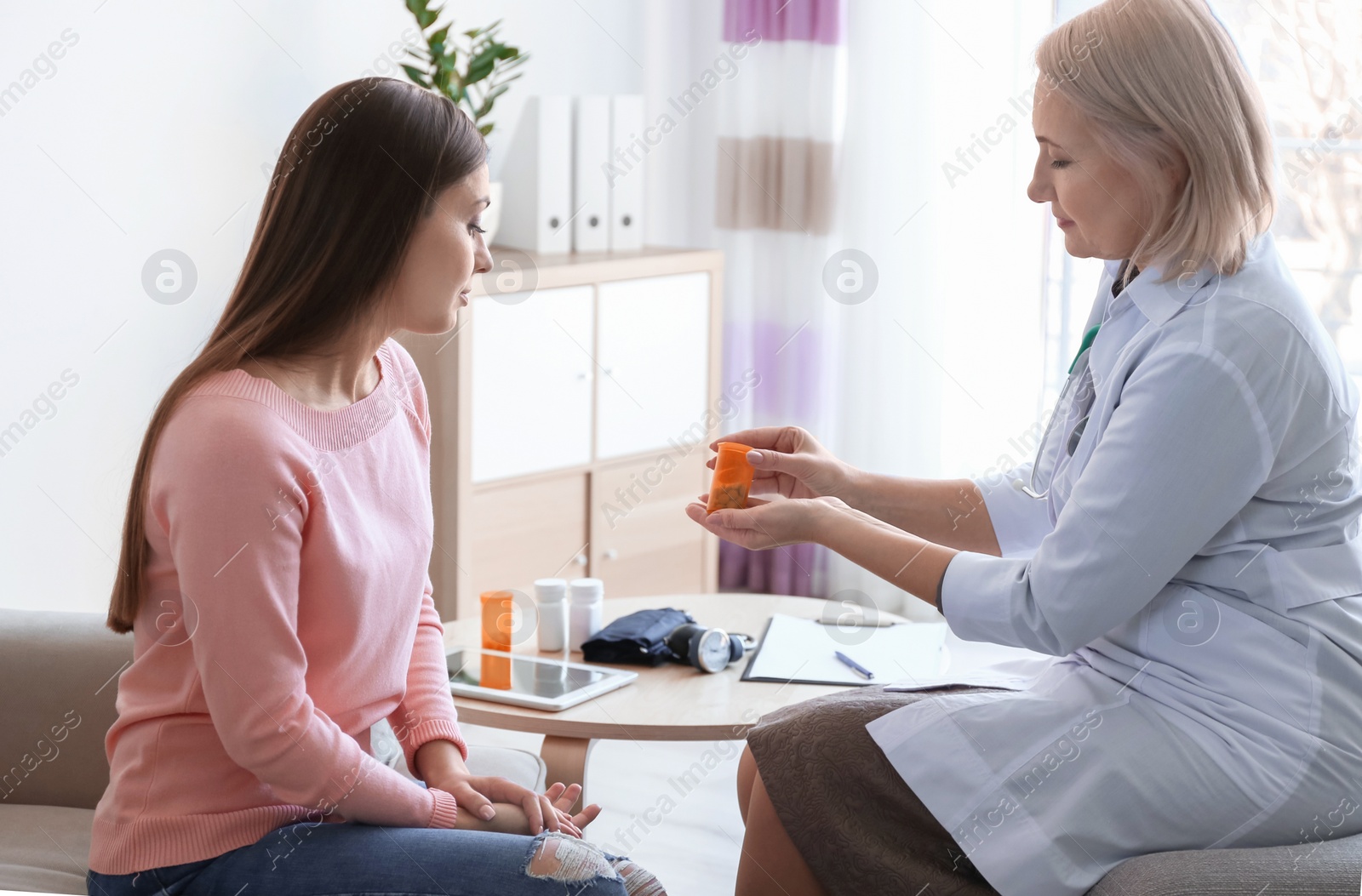 Photo of Mature doctor consulting patient at home