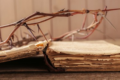Photo of Crown of thorns and Bible on wooden table, closeup