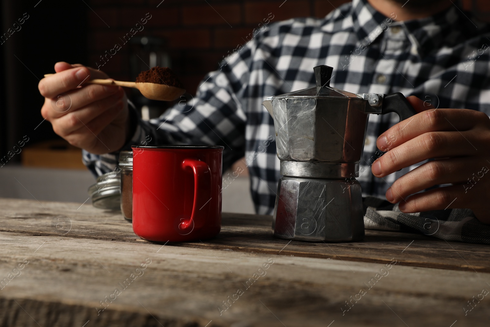 Photo of Man with moka pot and ground coffee at wooden table, closeup