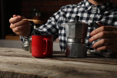 Photo of Man with moka pot and ground coffee at wooden table, closeup