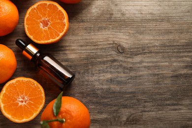 Photo of Flat lay composition with tangerine essential oil on wooden table, space for text