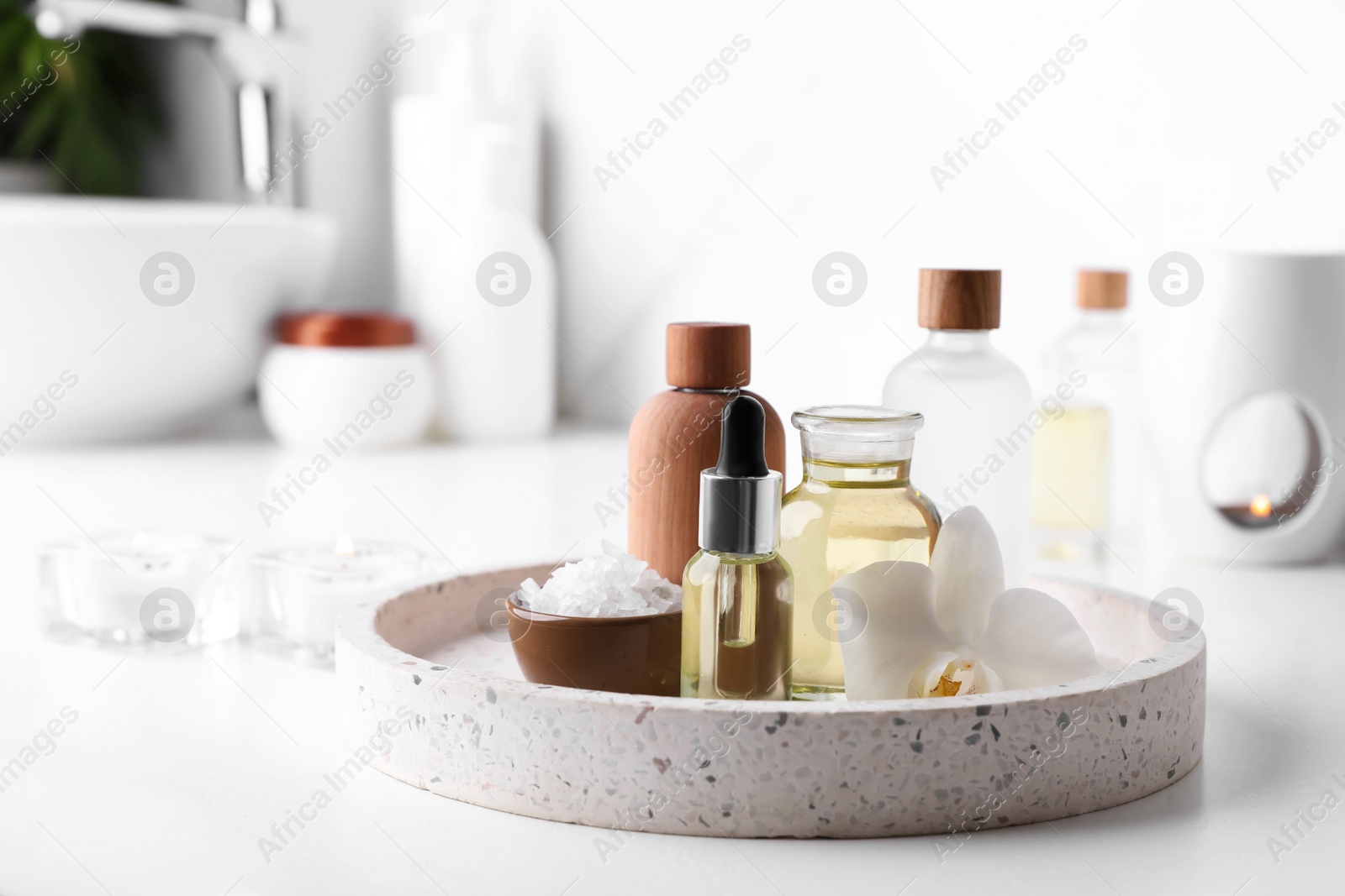 Photo of Essential oils, sea salt and orchid flower on white table in bathroom. Space for text