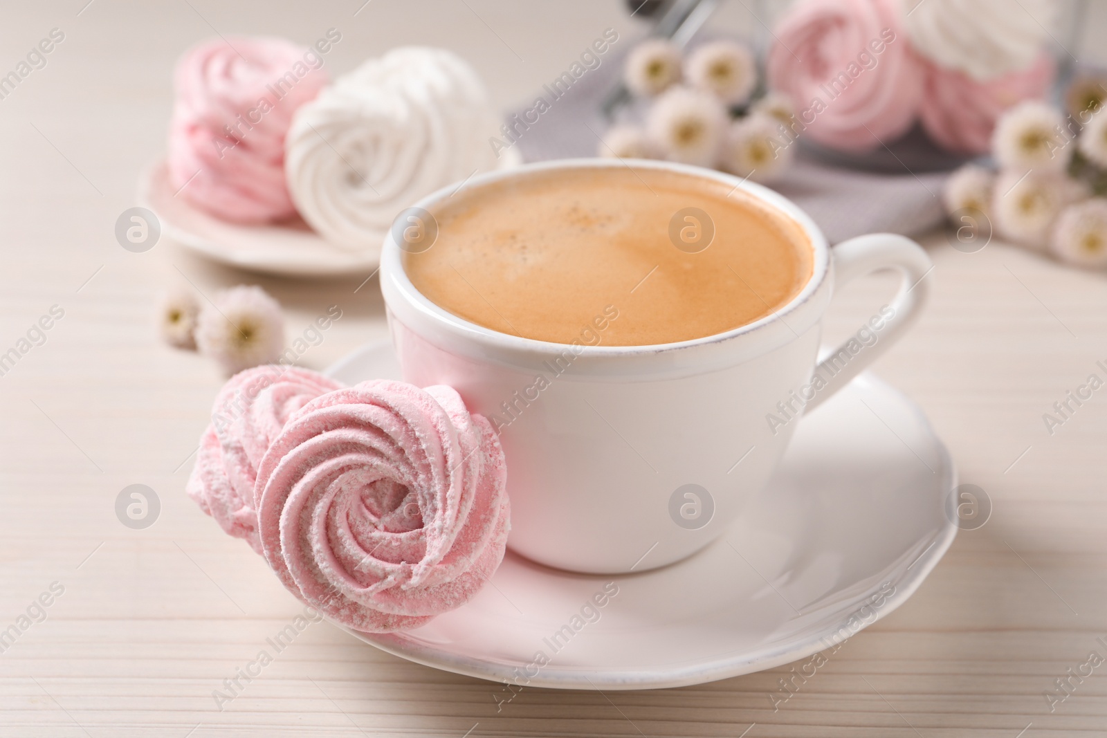 Photo of Delicious pink marshmallows and cup of coffee on wooden table